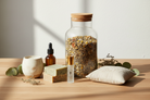 a collection of self care items (like herbal tea, tincture, candle, soap, roller perfume, and a dream pillow) on a table