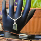 display hand hanging large moldavite pendant in sterling silver setting on chain