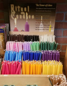 short tapered candles separates by color on display for spells and prayers